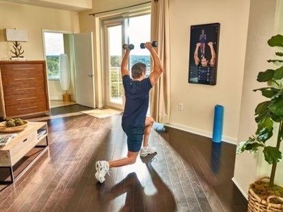 Um homem se exercita em casa em frente a um espelho de treino inteligente Echelon Reflect.